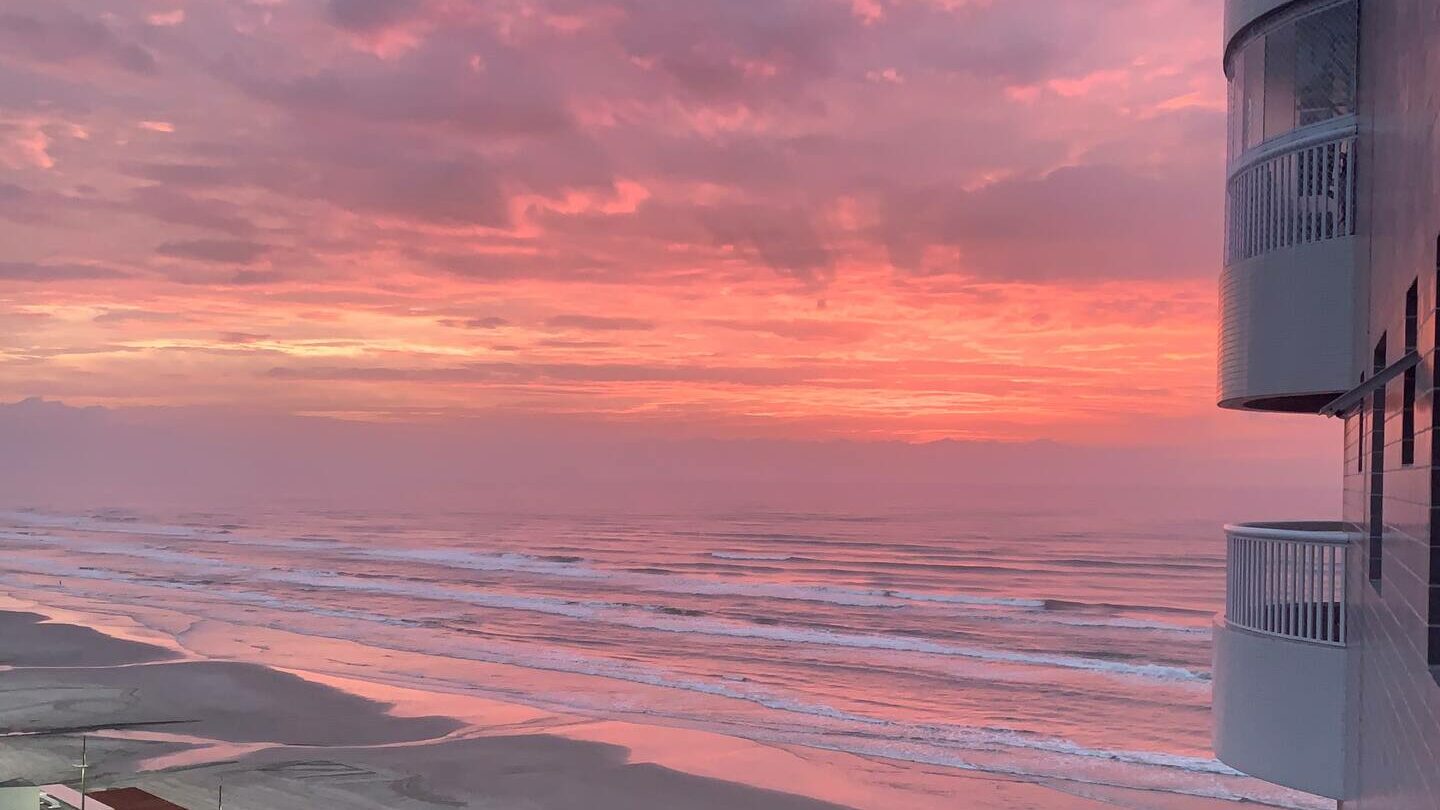 imagem do mar com céu vermelho no nascer do sol, vista da sacada no apartamento vista mar